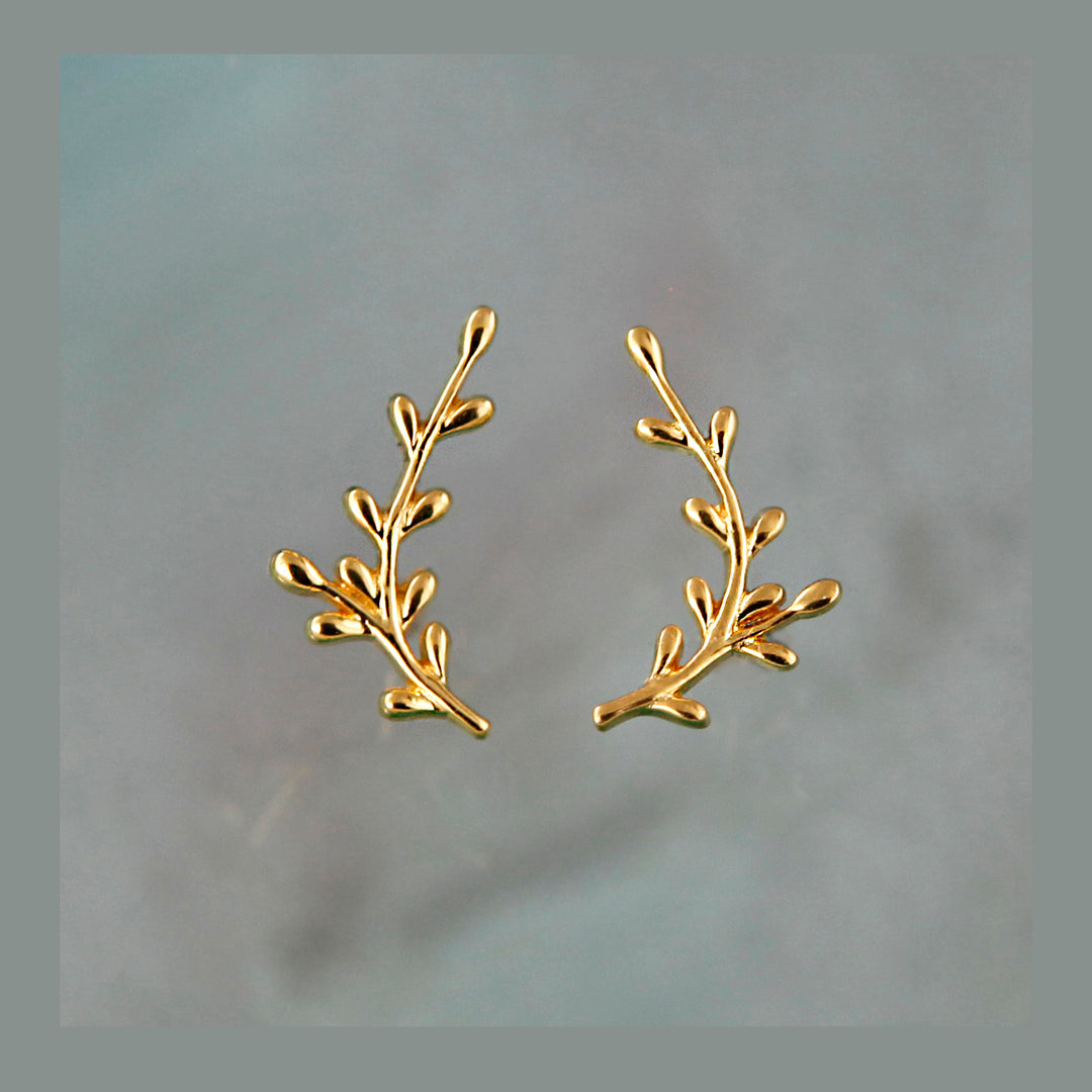 Pair of gold branch-shaped earrings on a light gray background
