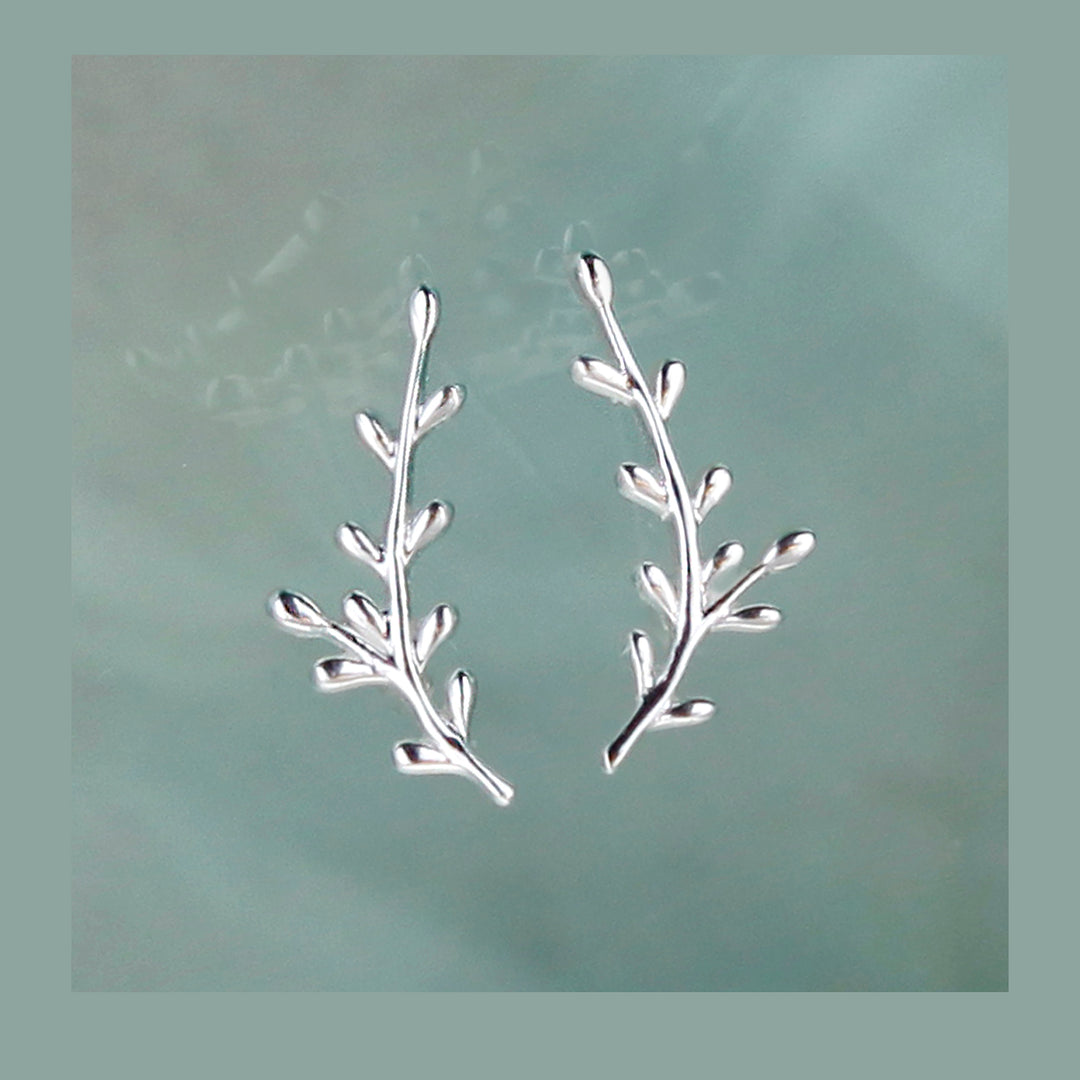 Silver leaf-shaped earrings on a light gray background