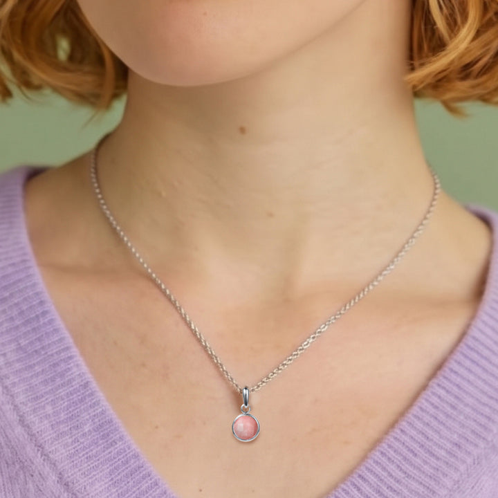 Close-up of woman wearing a pink opal gemstone pendant in sterling silver