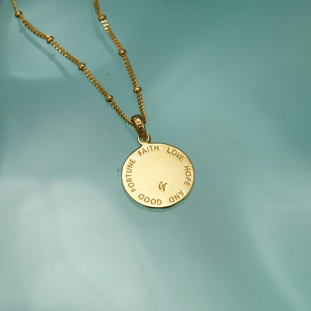 Reverse of a gold four leaf clover lucky charm necklace with etched message .
