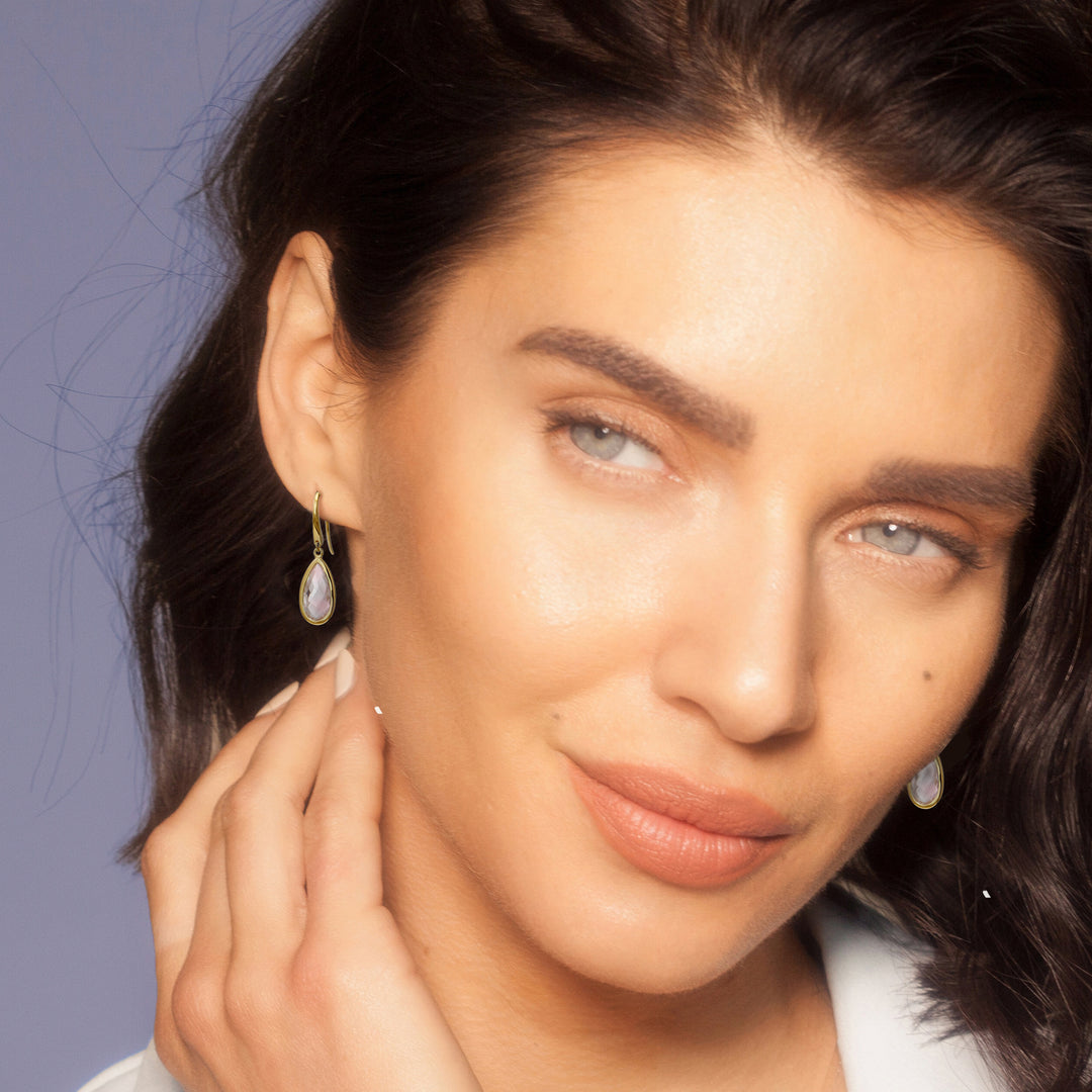 Close-up of model wearing pale pink teardrop earrings in gold vermeil on hooks.