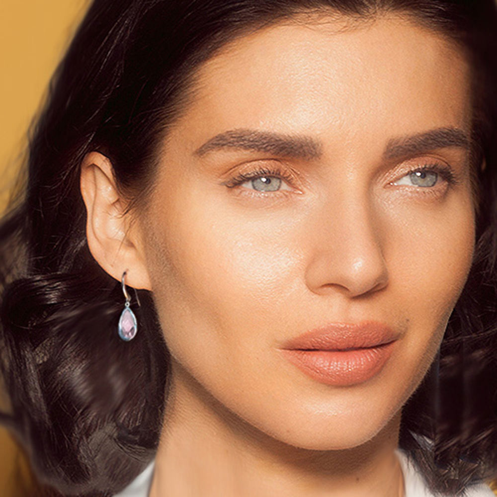 Close-up of a woman with wearing pale pink teardrop shaped earrings in silver and rose quartz.
