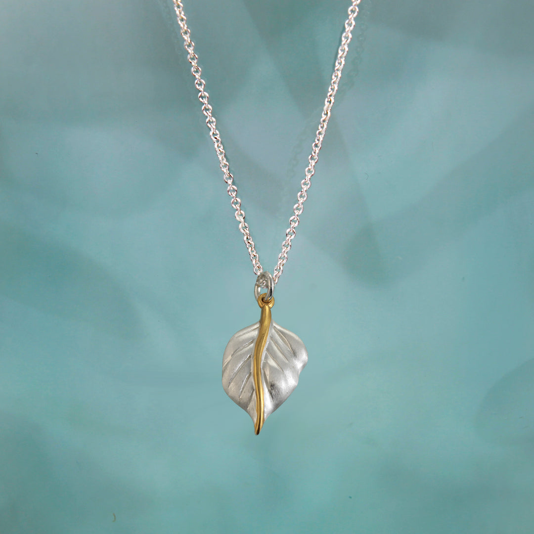 silver leaf necklace with gold details on a blue background