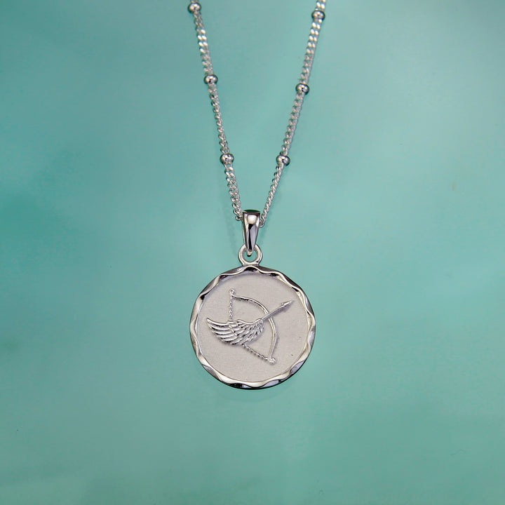 Silver sagittarius star sign necklace on an aqua background