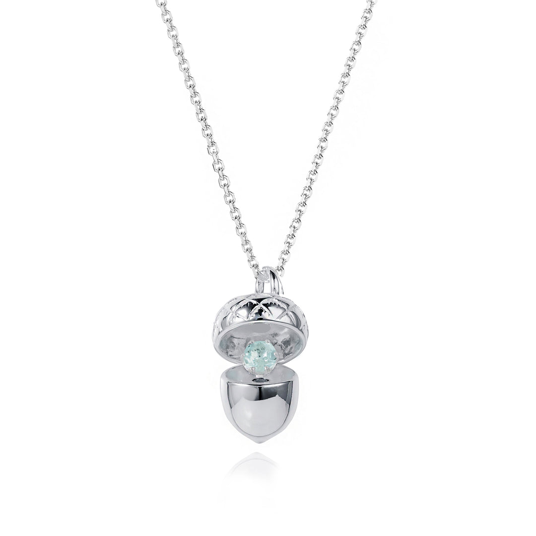 Silver acorn locket opened up to show an aquamarine march birthstone on a white background