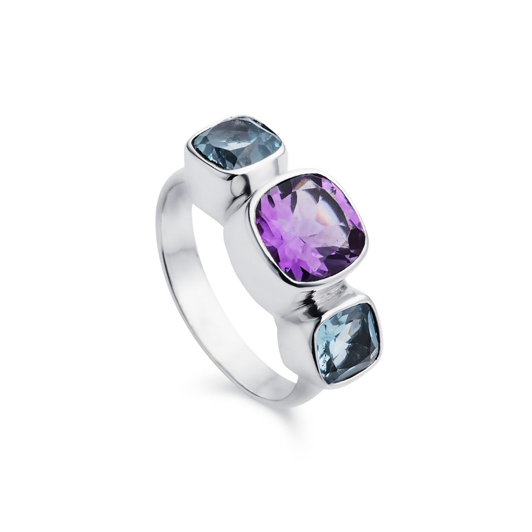 Silver three stone ring with amethyst and blue topaz gemstones on a white background