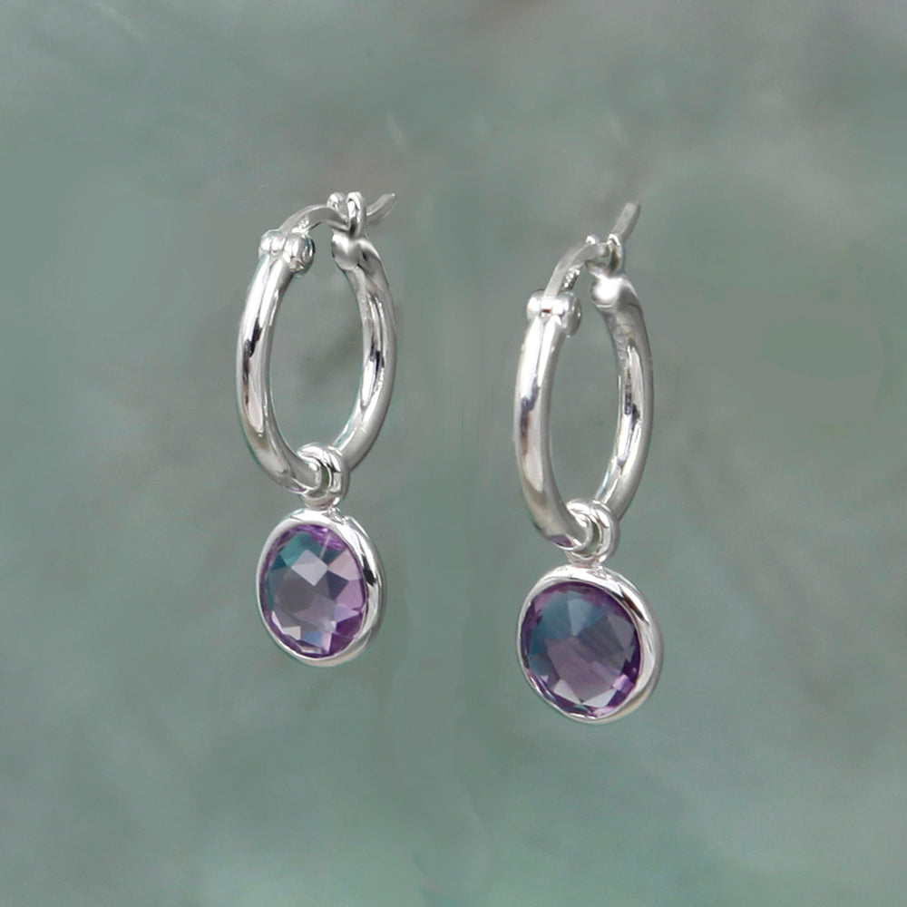 Sterling silver amethyst huggie hoop earrings on a grey background