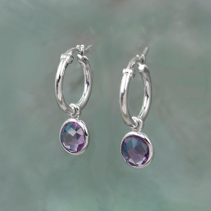 Silver hoop earrings with purple gemstones on a gray background