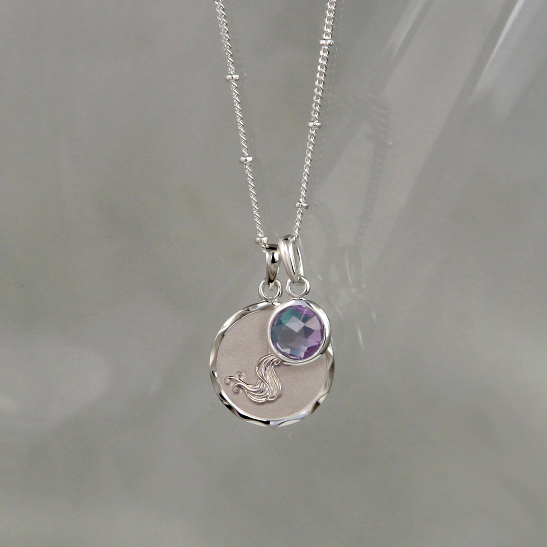 Silver aquarius zodiac pendant with an amethyst february  birthstone charm on gray background