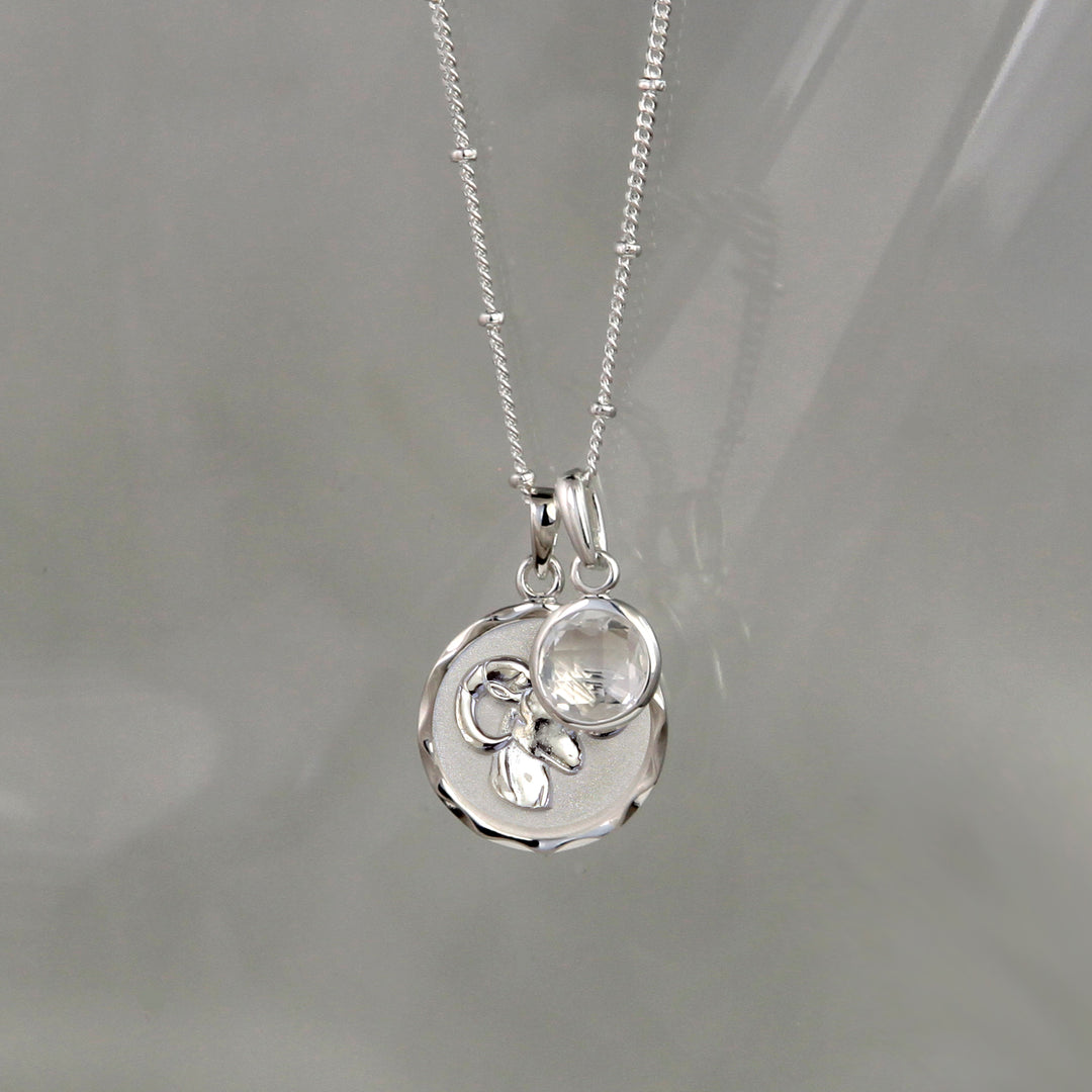 Silver Aries zodiac pendant and chain with silver topaz birthstone charm on gray background