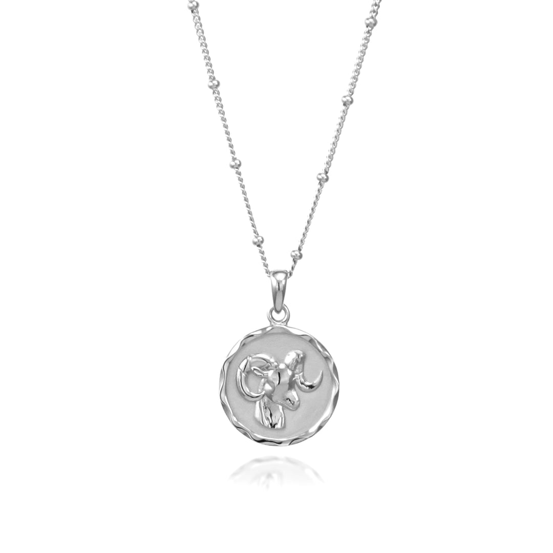 Silver aries zodiac pendant and beaded chain against a white background