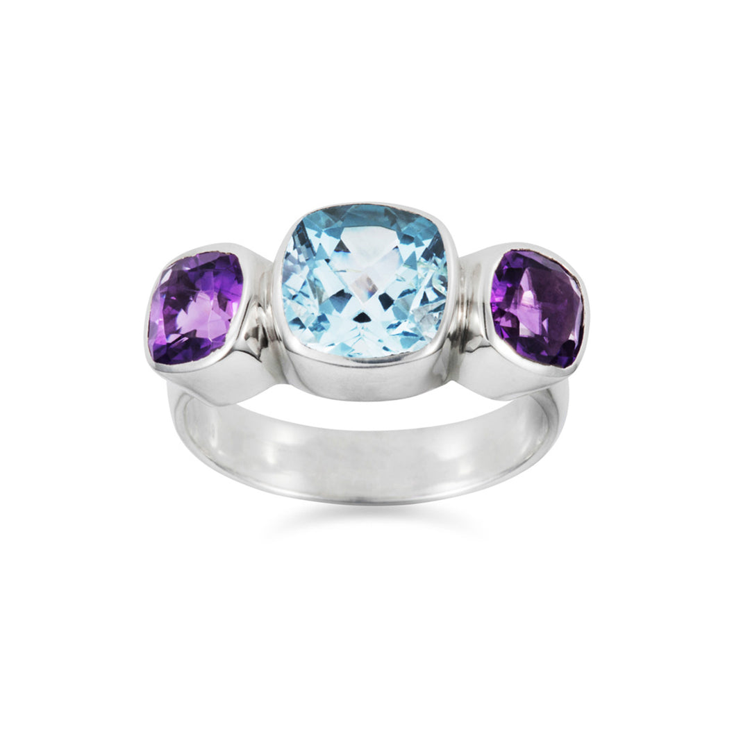 Front view of a silver three stone ring set with amethysts and blue topaz on white background