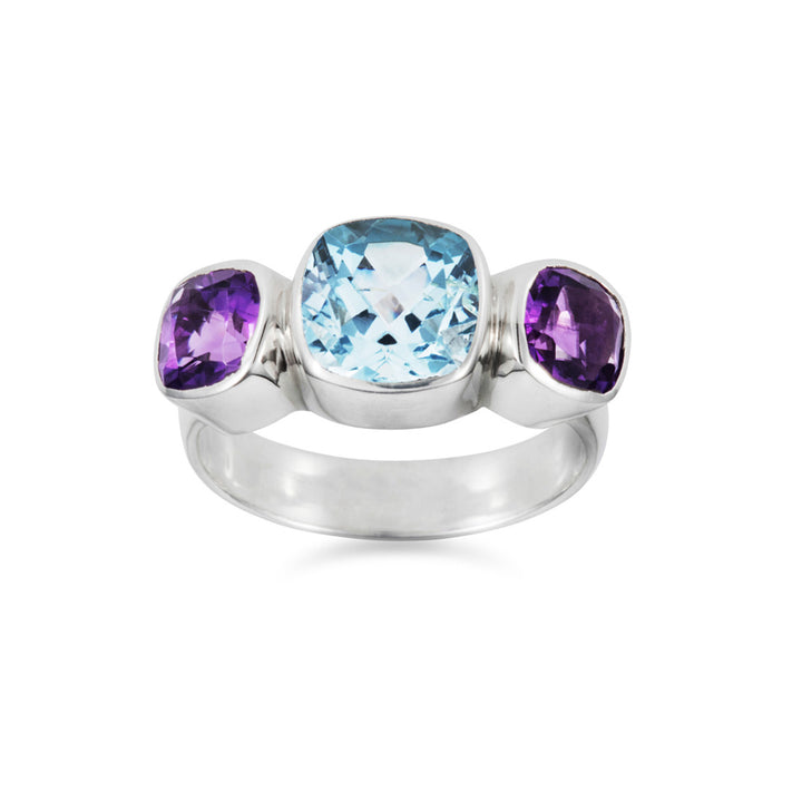 Front view of a silver three stone ring set with amethysts and blue topaz on white background