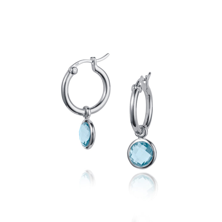 Silver snap post huggie hoop earrings with blue gemstones on white background