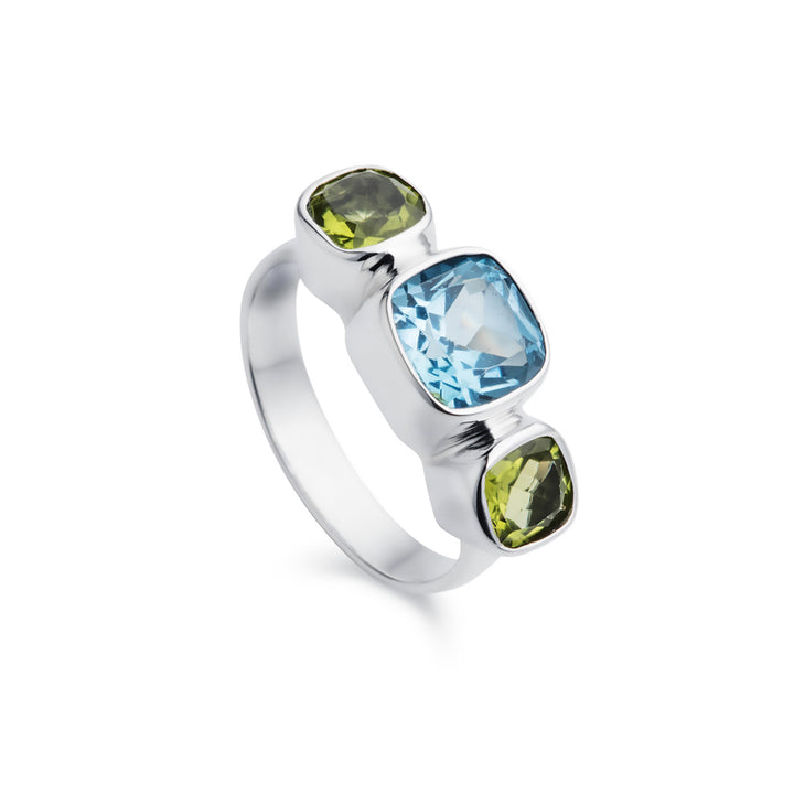 Silver three stone ring with blue topaz and peridot gemstones on a white background
