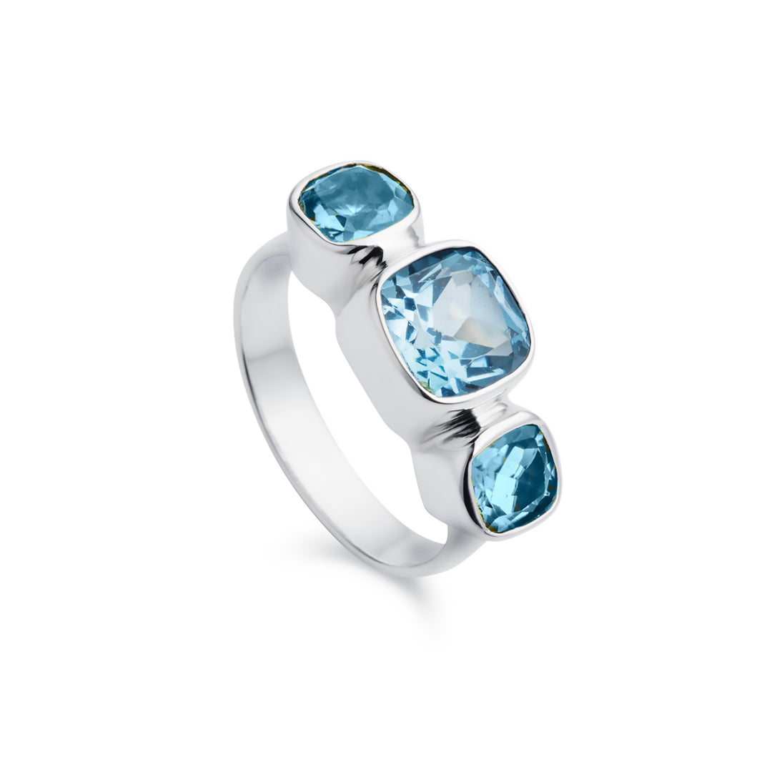 Blue topaz three stone ring set in silver on a white background