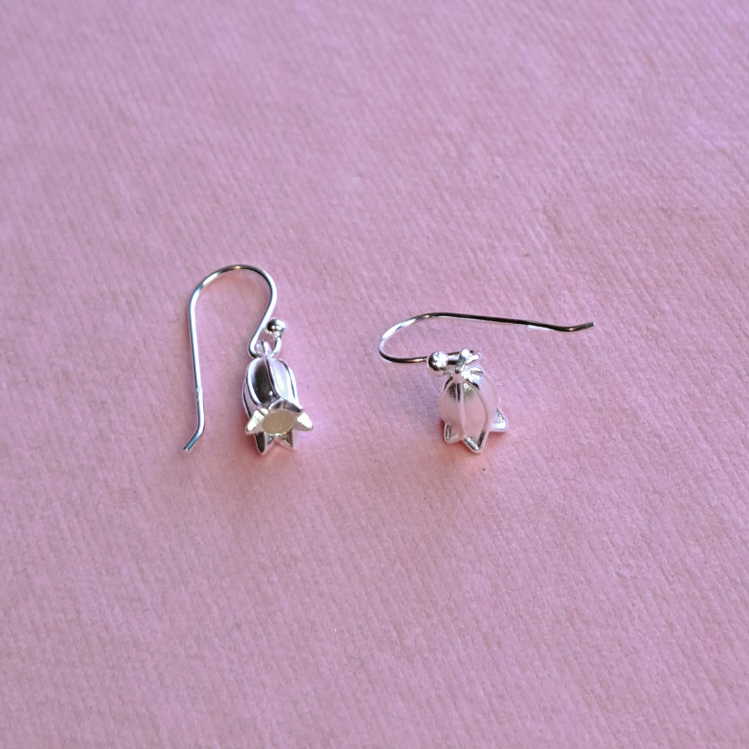 Sterling silver small bluebell hook earrings, alternative view on pink watercolour paper