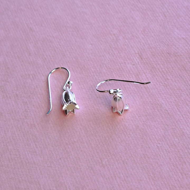 Sterling silver small bluebell hook earrings, alternative view on pink watercolour paper