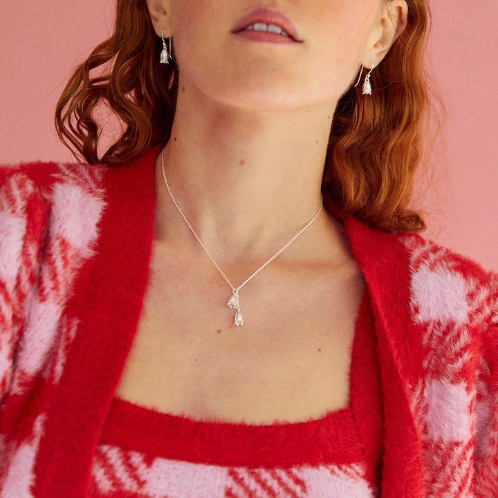 Close-up of a model wearing silver bluebell shaped silver necklace and matching earrings