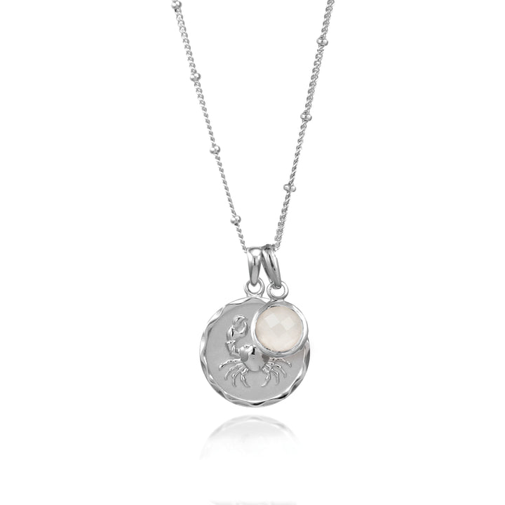 SIlver cancer zodiac pendant and moonstone June birthstone charm on a white background