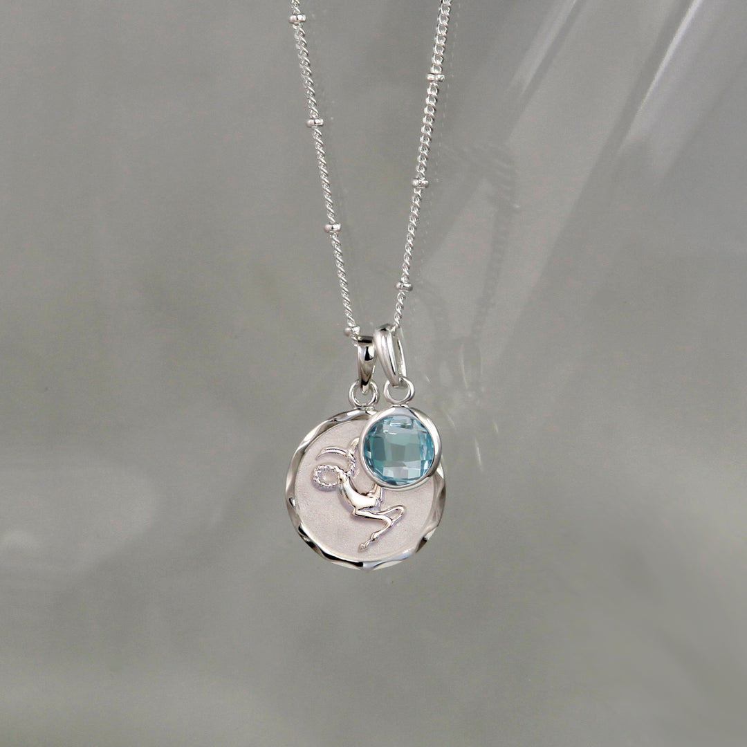 Silver capricorn zodiac necklace with a blue topaz december birthstone charm