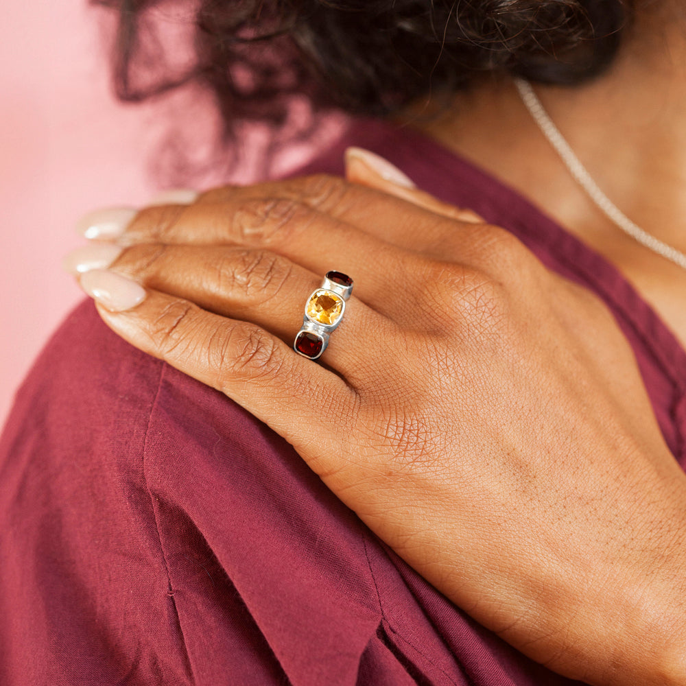 Model wearing a silver ring with yellow and red gemstones with a red dress