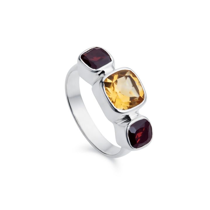 Silver three stone ring with cushion-cut citrine and garnets on a white background