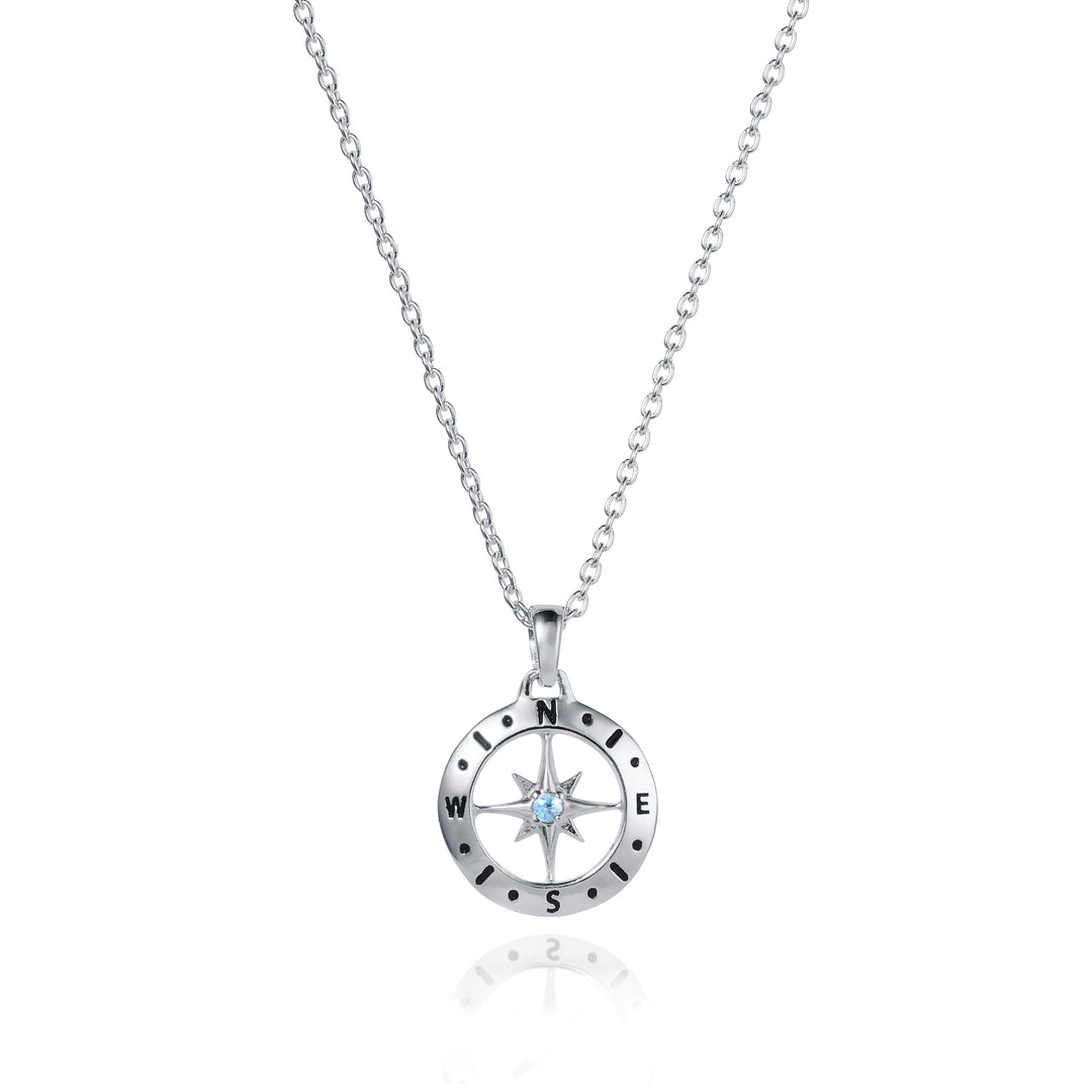 Dainty silver compass pendant with aquamarine March birthstone on white background