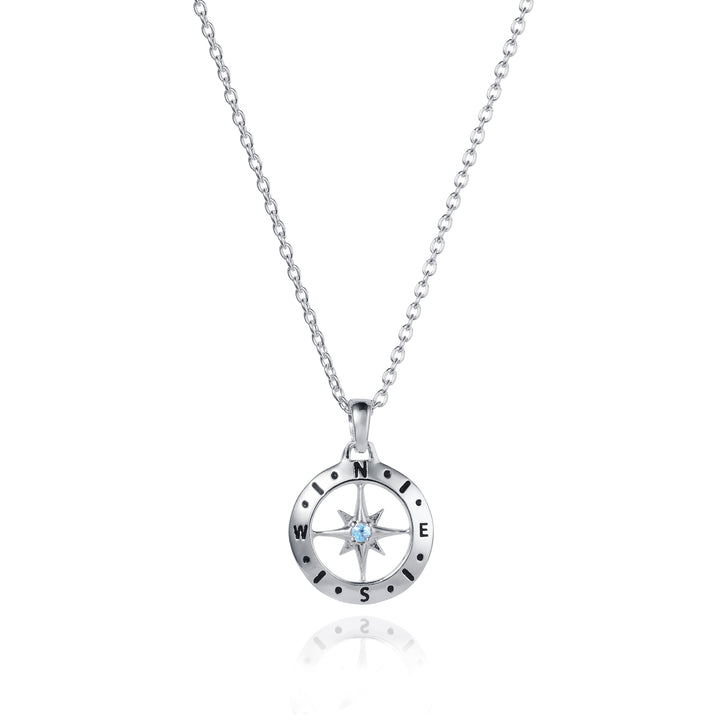 Dainty silver compass pendant with aquamarine March birthstone on white background