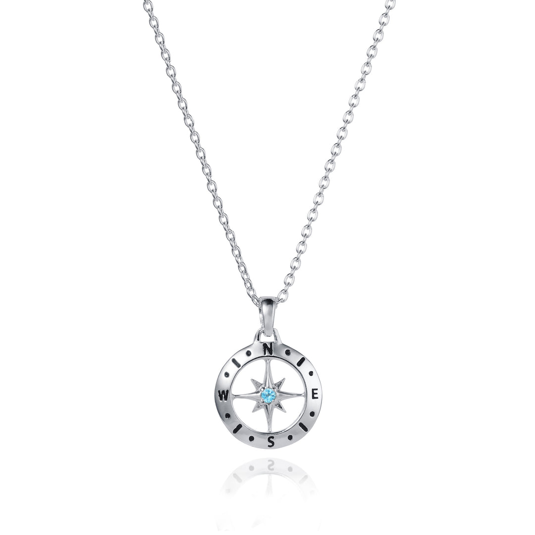 Dainty silver compass pendant with blue topaz December birthstone on white background
