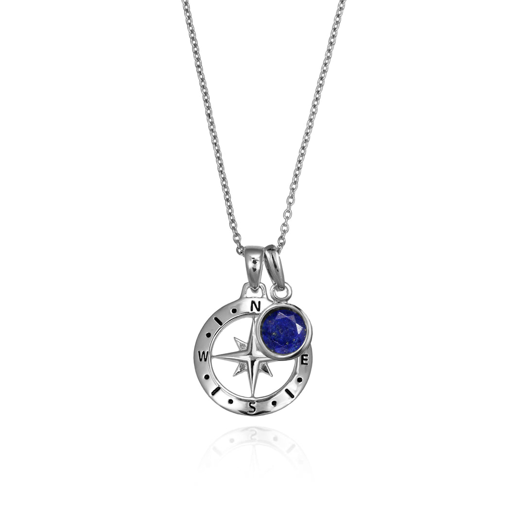 Silver compass necklace with an dark blue lapis september birthstone charm pendant and chain on a white background