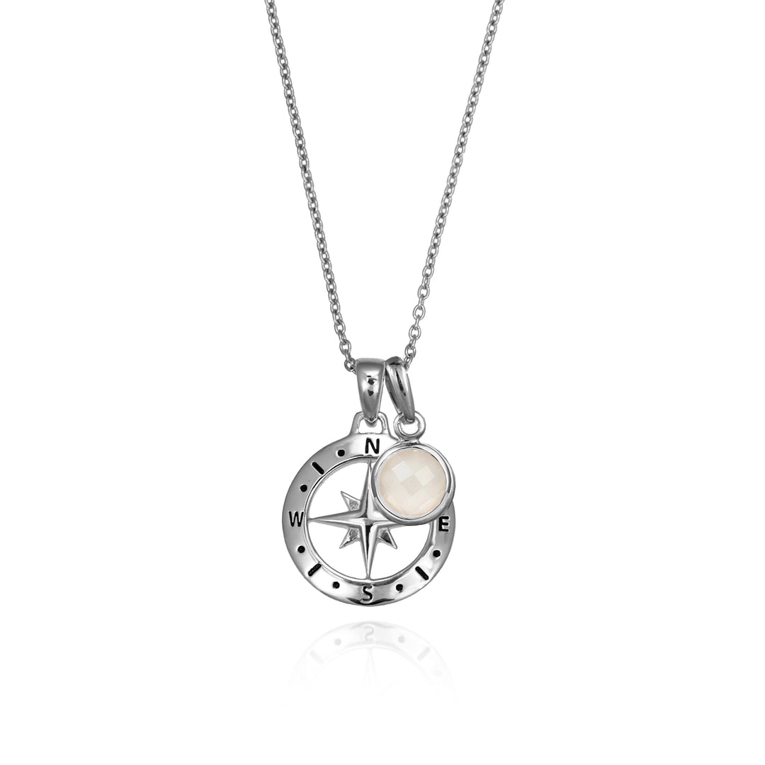 Silver compass necklace with a moonstone june birthstone charm pendant and chain on a white background