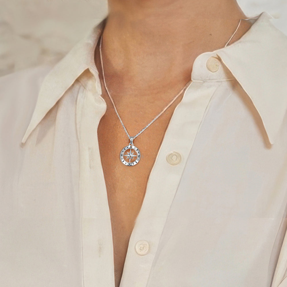 Close-up of silver compass necklace on a woman