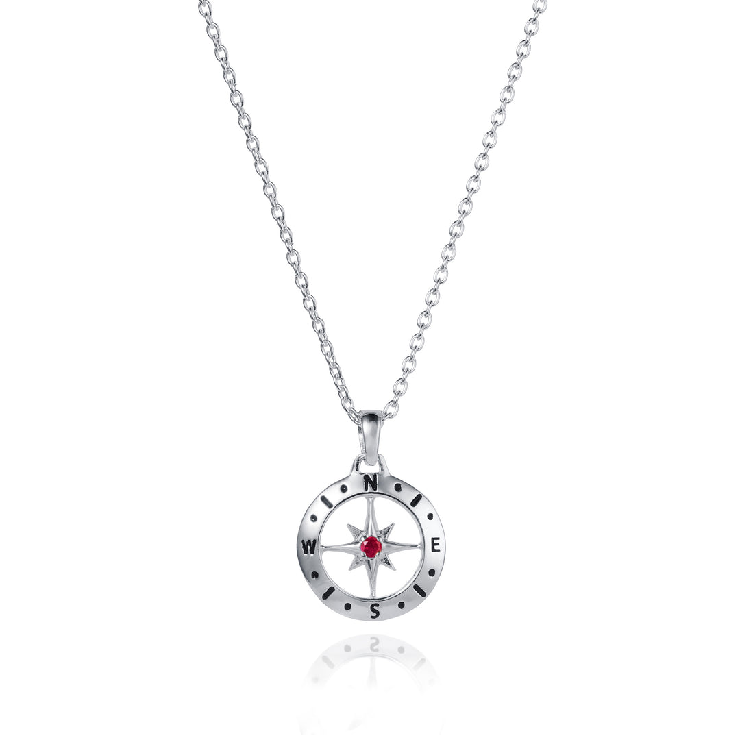 Dainty silver compass pendant with ruby July birthstone on white background