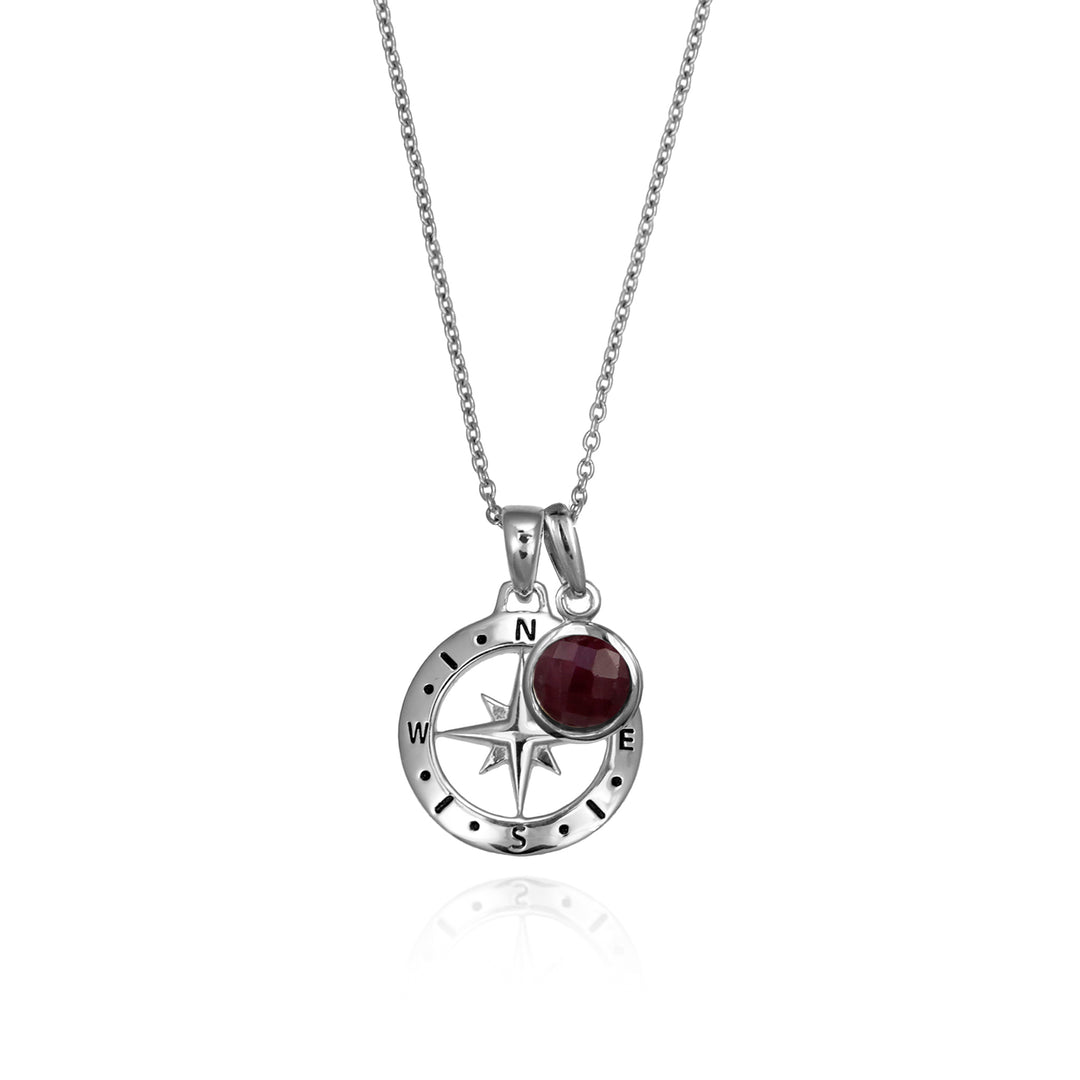 Silver compass necklace with a red ruby july birthstone charm pendant and chain on a white background