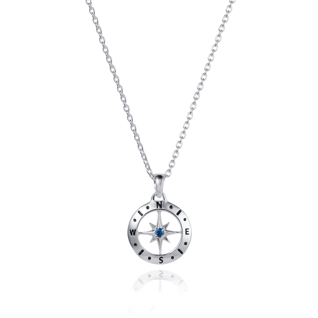 Dainty silver compass pendant with sapphire September birthstone on white background