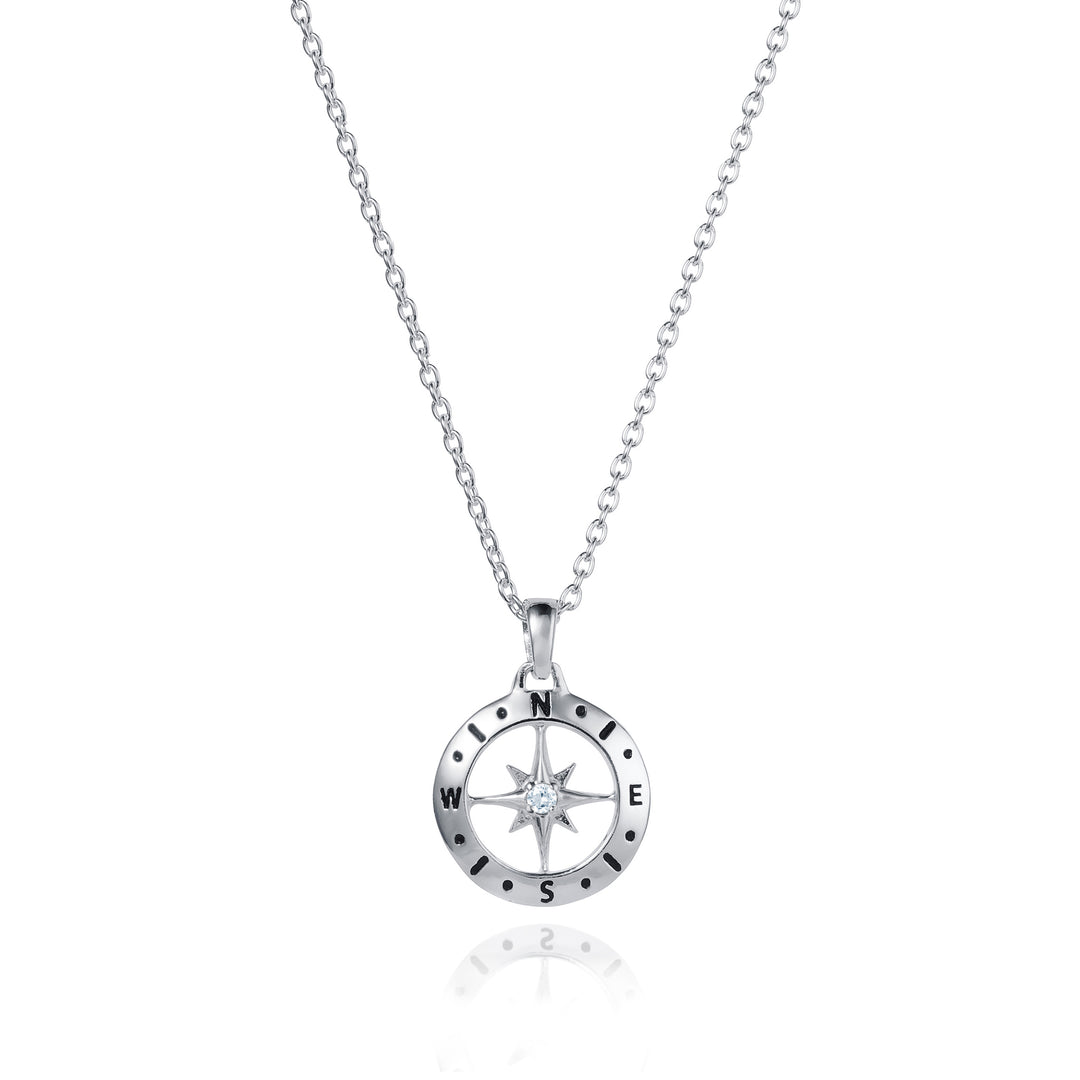 Dainty silver compass pendant with white topaz April birthstone on white background