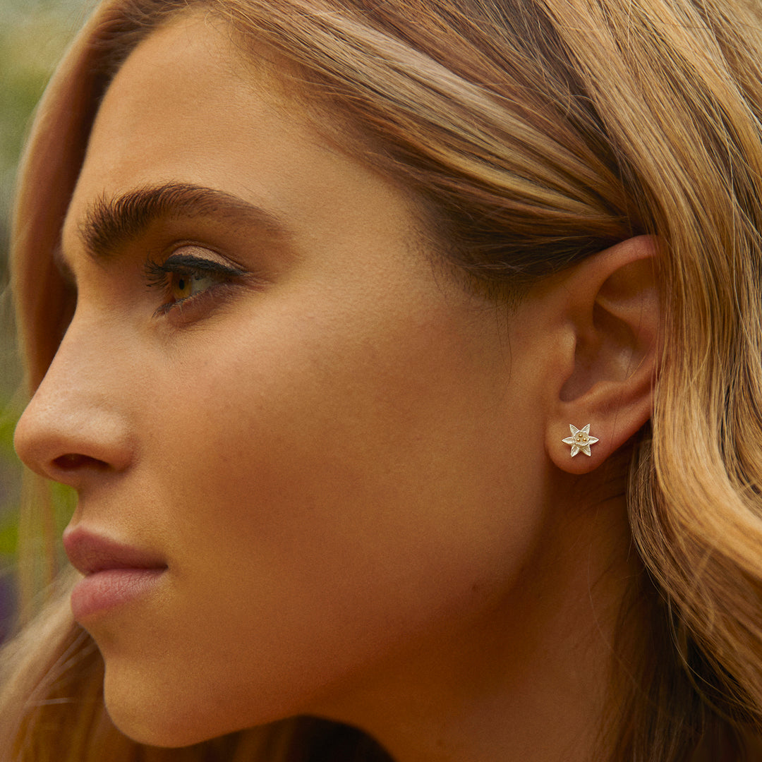 Close-up of a woman wearing a daffodil-shaped earring outdoors