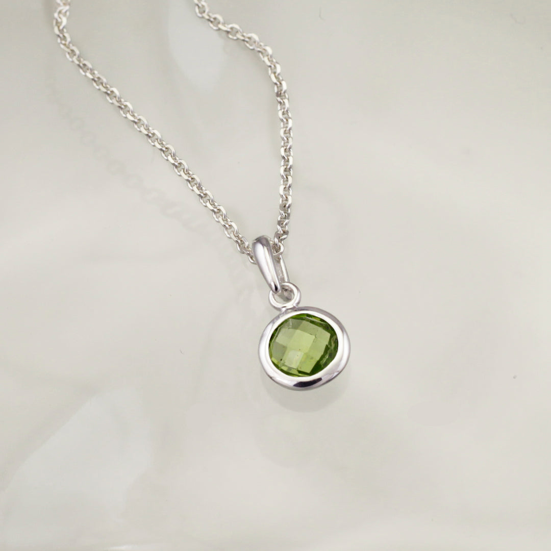 Silver necklace with a green gemstone pendant on a light gray background
