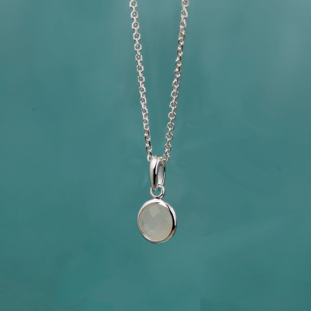 silver moonstone necklace on an aqua background.