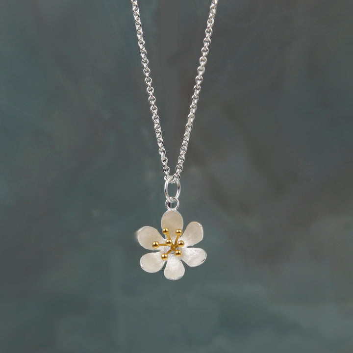 Silver daisy flower necklace on a dark gray background