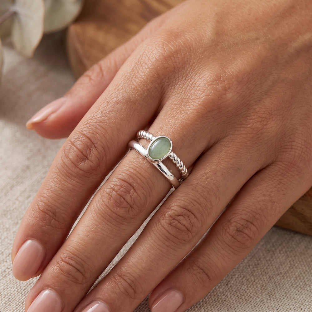 A hand with a sterling silver double band ring with green aventurine cabochon
