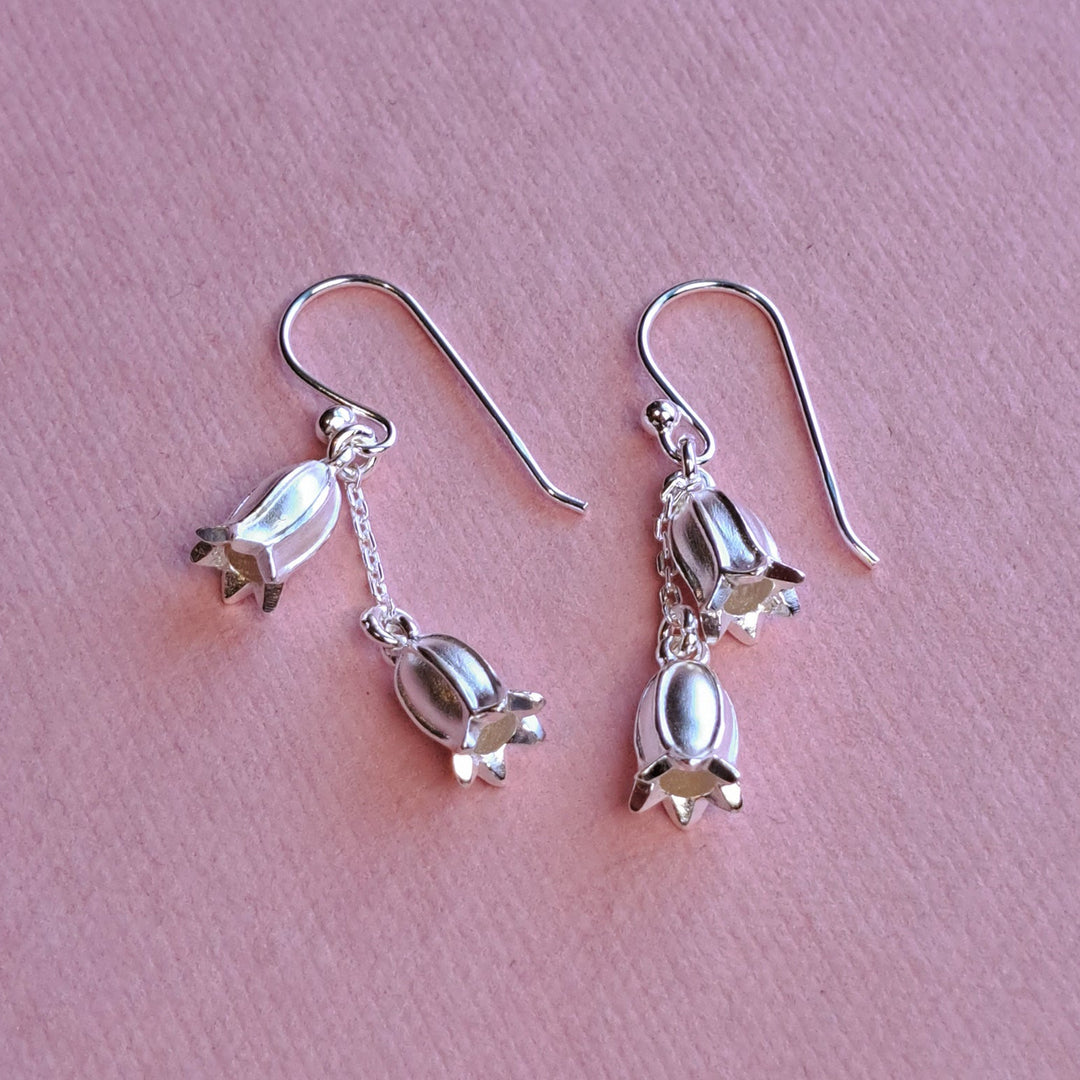 Sterling silver long drop double bluebell earrings, alternative view on pink watercolour paper
