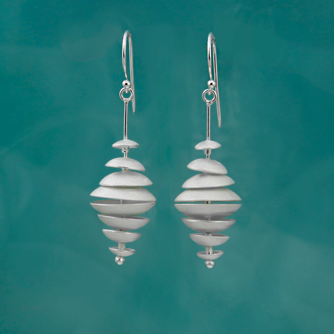 Pair of silver multiple disk earrings on a teal background