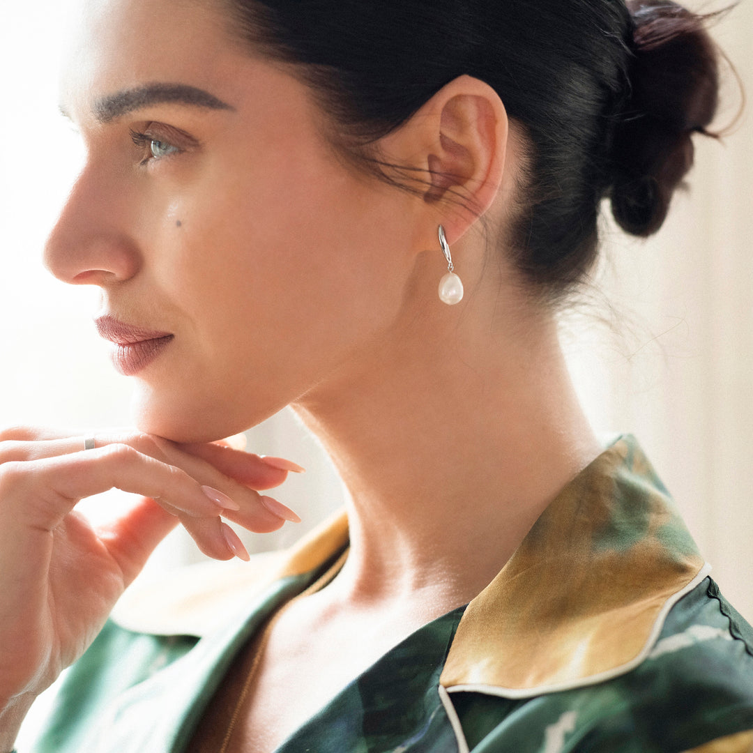 Side view of model wearing silver drop post earring with a freshwater pearl 