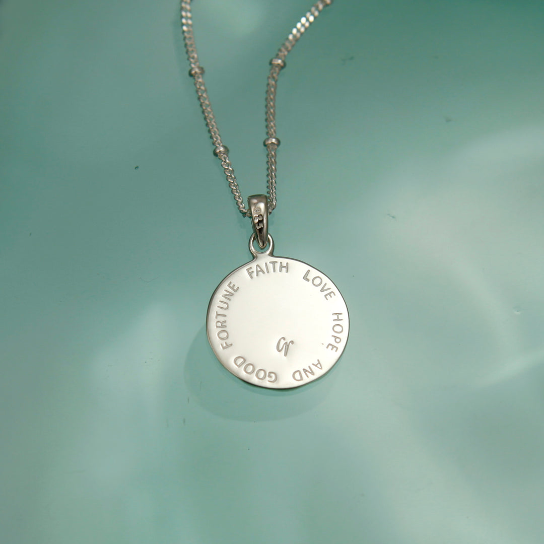 Reverse side of a personalised four-leaf necklace with a message on a green background