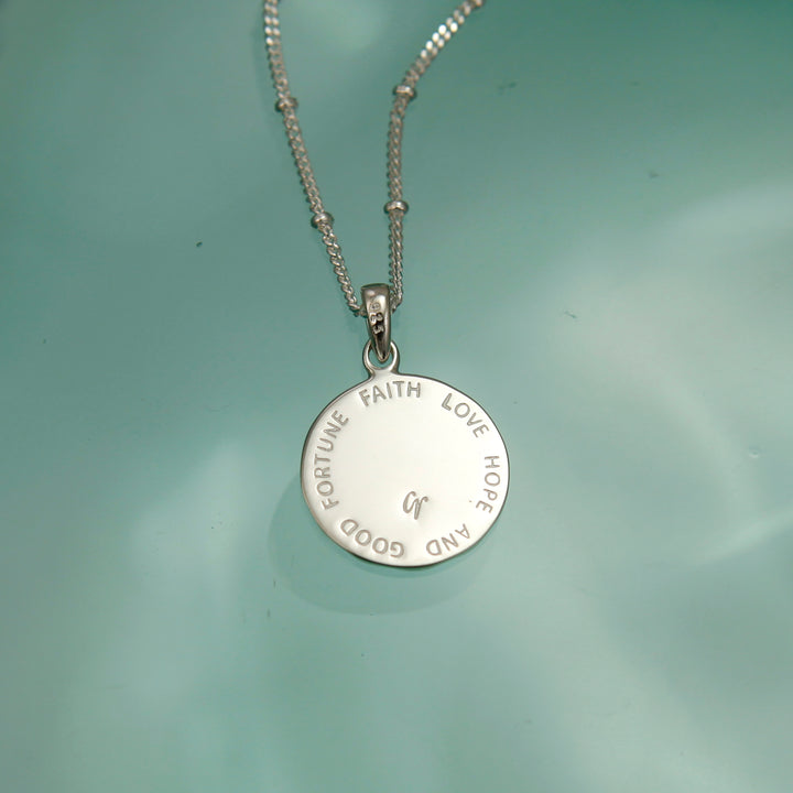 Reverse side of a personalised four-leaf necklace with a message on a green background