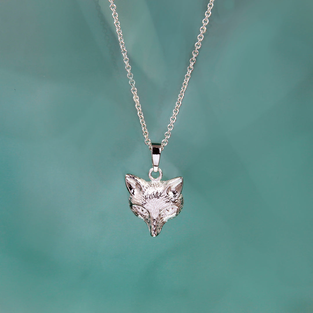 Silver fox head pendant necklace on a green background