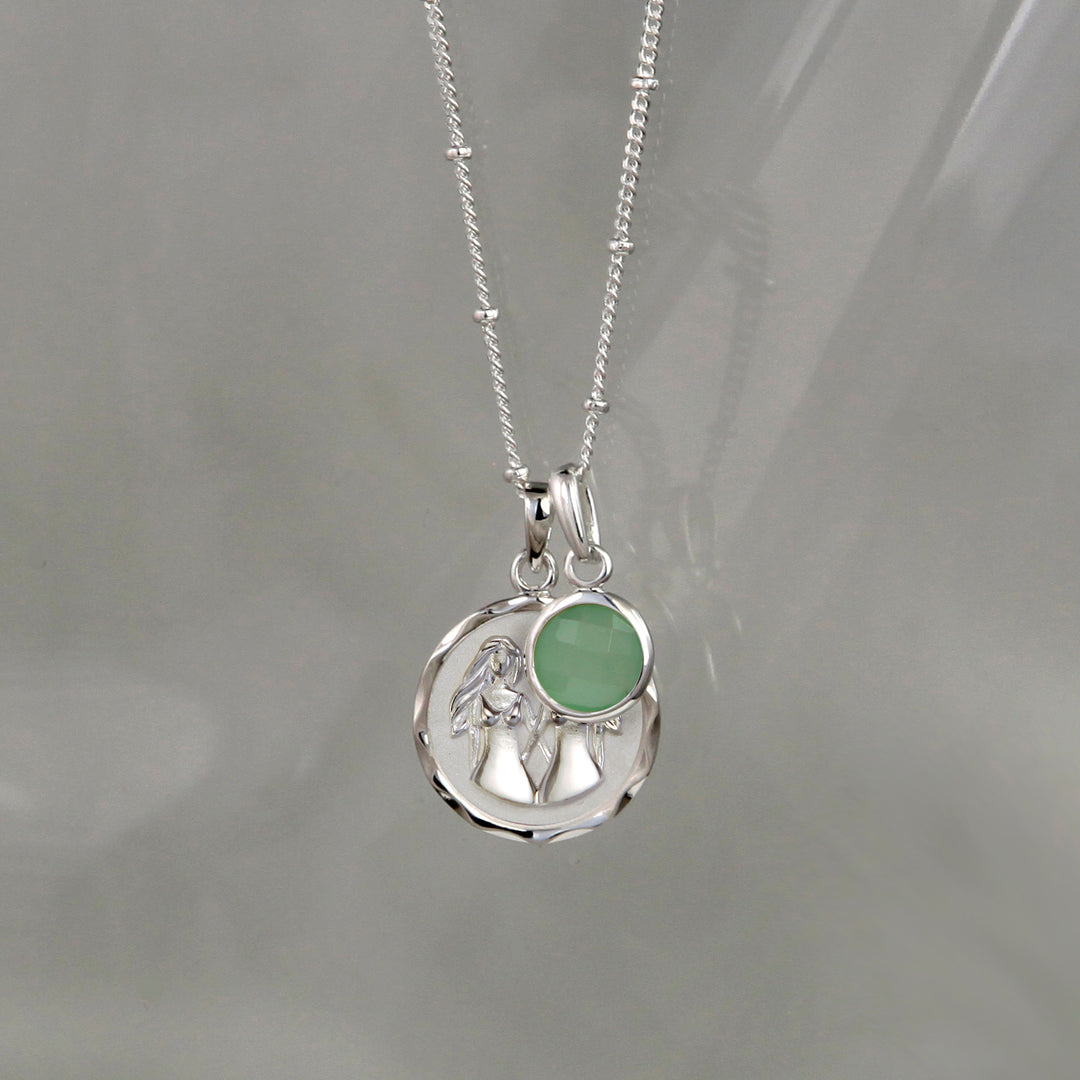 Silver gemini zodiac pendant and green quartz May birthstone charm on a gray background
