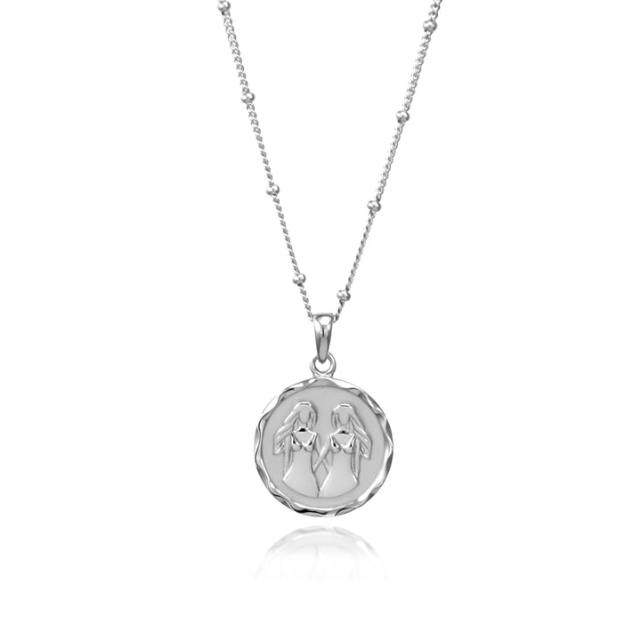 Silver Gemini zodiac pendant and beaded silver chain on a white background